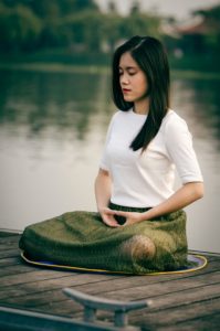 mulher meditando à beira do lago